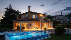Ein zweistöckiges Haus mit Swimmingpool, Sitzgelegenheiten im Freien und Satellitenschüsseln.