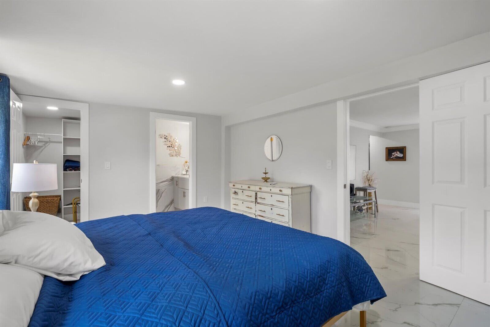 A bedroom with a bed, a dresser, a mirror, and a wardrobe.