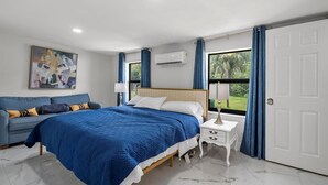 A hotel room with a bed, a nightstand, a lamp, a sofa, and a painting on the wall. - 3-Bedroom Punta Gorda Retreat (Punta Gorda)