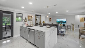 A modern kitchen with a marble countertop, grey cabinets, and a built-in dishwasher. - 3-Bedroom Punta Gorda Retreat (Punta Gorda)