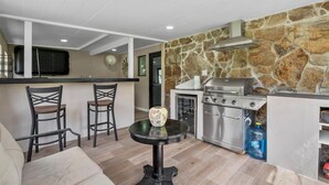 A compact kitchen with a stone wall, a grill, and a small dining area with two chairs. - 3-Bedroom Punta Gorda Retreat (Punta Gorda)
