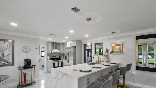 A modern kitchen with a marble island, stainless steel appliances, and a bar area with stools. - 3-Bedroom Punta Gorda Retreat (Punta Gorda)