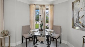 A dining area with a round table, two chairs, a vase with flowers, and a painting on the wall. - 3-Bedroom Punta Gorda Retreat (Punta Gorda)
