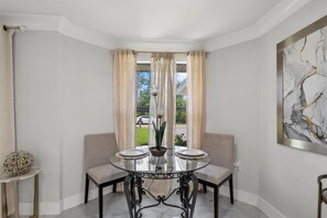 A dining area with a round table, two chairs, a vase with flowers, and a painting on the wall. - 3-Bedroom Punta Gorda Retreat (Punta Gorda)