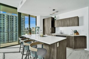 Eine moderne Küche mit einer großen Kochinsel, Barhocker und Blick auf die Stadtlandschaft.