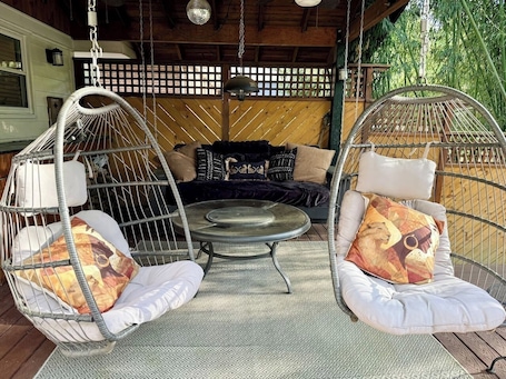 Two hanging chairs with cushions, a round table, and a wooden deck.. 6BR Near Emory / CHOA / Beth Jacob - Sleeps 10-16