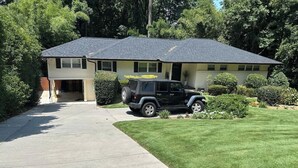 A two-story house with a driveway, a lawn, and a parked SUV.