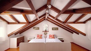 Ein Schlafzimmer mit Gewölbedecke, einem Bett mit floralen Kissen, einem Nachttisch und einem kleinen Schrank.