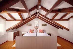 Ein Schlafzimmer mit Gewölbedecke, einem Bett mit floralen Kissen, einem Nachttisch und einem kleinen Schrank.