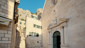 Eine enge Gasse mit Steinbauten, einer Treppe und einer grünen Tür mit einem verzierten Bogen.