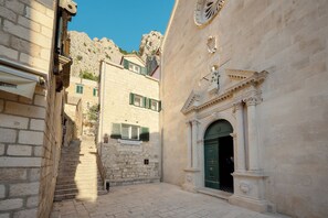Eine enge Gasse mit Steinbauten, einer Treppe und einer grünen Tür mit einem verzierten Bogen.