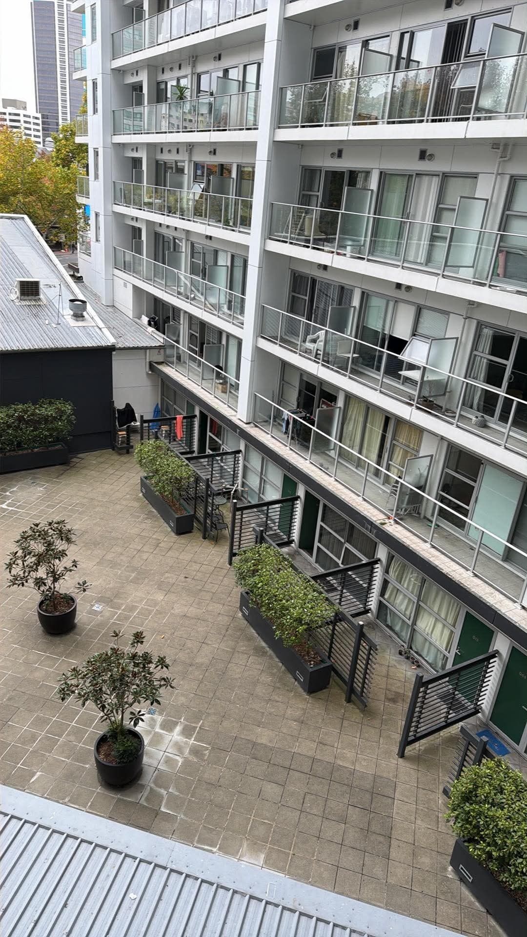 A multi-story building with balconies, potted plants, and a tiled courtyard.