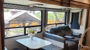 Interior acogedor de una autocaravana, con comedor, asientos y vistas al exterior.