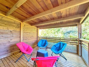 Ein überdachter Außenbereich mit Holzboden, Metallgeländern und zwei Klappstühlen.