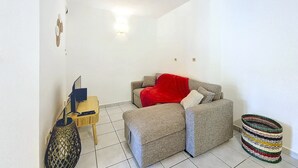 Una habitación pequeña y luminosa, con un sofá, una mesita y una cesta decorativa.