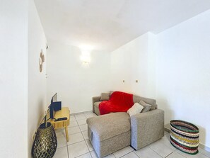 Ein kleiner, gut beleuchteter Raum mit einer Couch, einem kleinen Tisch und einem dekorativen Korb.