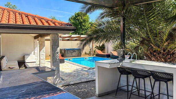 Uma área externa coberta com piscina, assentos e bar.