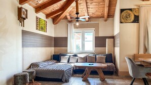 Um quarto aconchegante com teto de madeira, uma cama com cabeceira azul, uma mesa de madeira e uma cadeira.