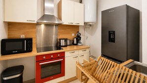 Cocina pequeña equipada con microondas, estufa, fregadero y refrigerador.