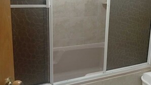 A bathroom with a shower enclosure, tiled walls, and a toilet.