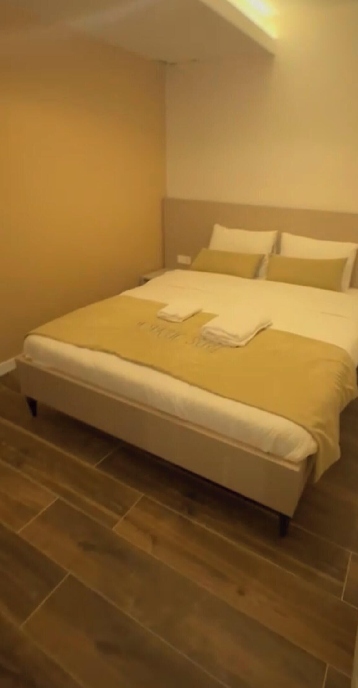 Habitación de hotel con cama, cabecero y suelo de madera.