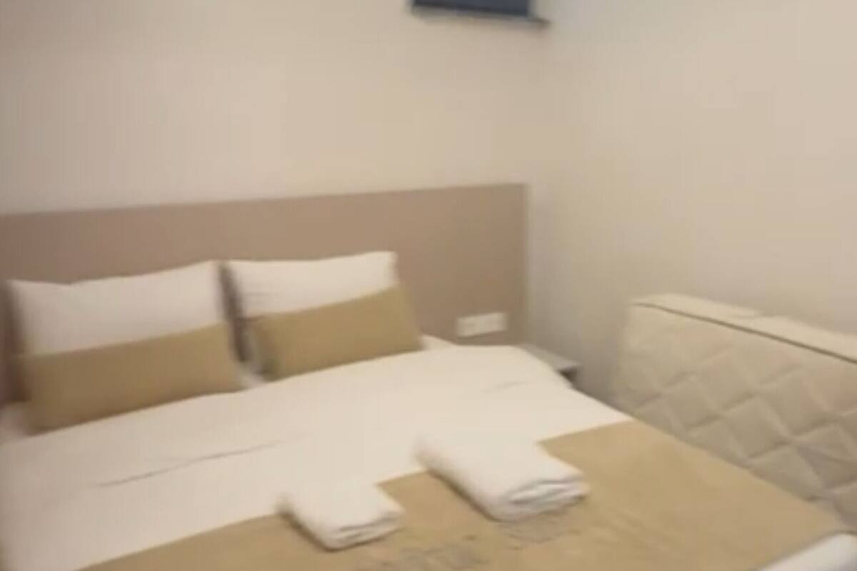 A hotel room with a bed, a small bedside table, and a ceiling light.
