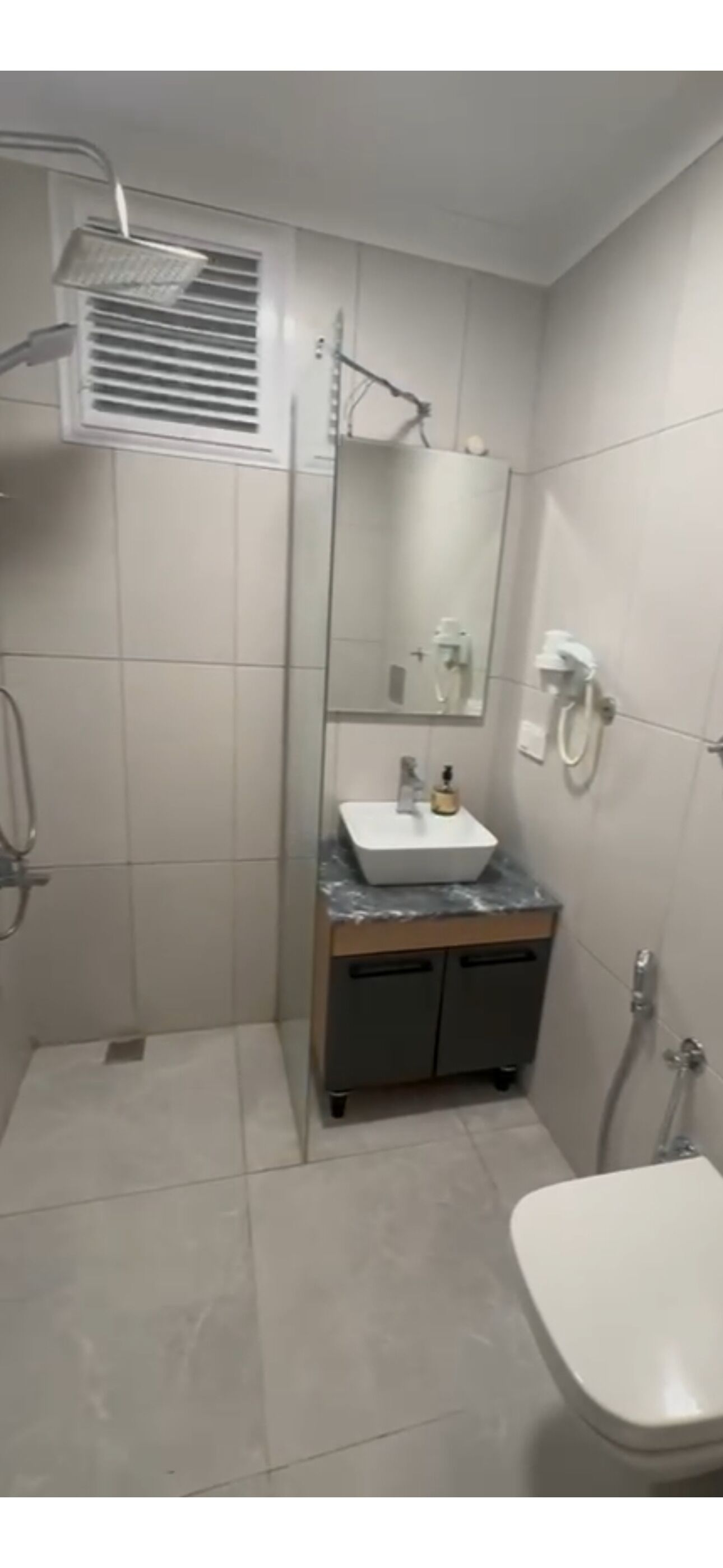 A bathroom with a shower, a sink, a toilet, and a mirror.