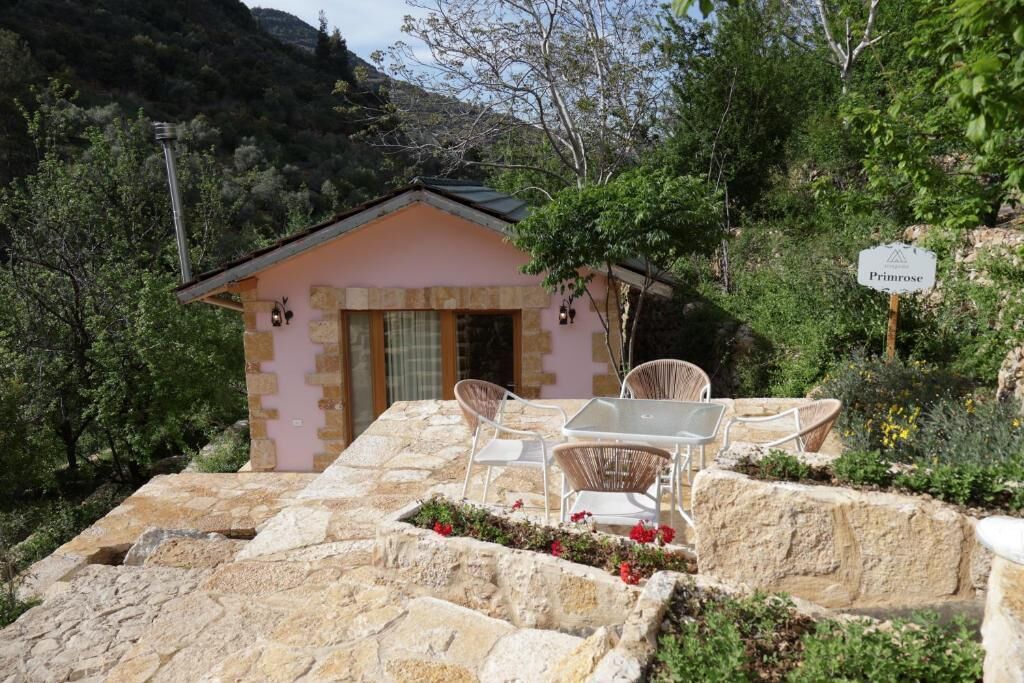A stone building with a pink facade, a patio with white wicker furniture, and a sign that reads 'Primrose.'