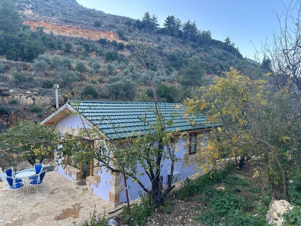 A house with a tiled roof, a patio with chairs, and a view of a hillside.