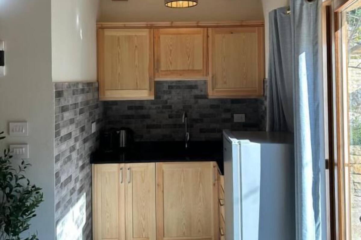 A kitchen with wooden cabinets, a black countertop, and a hanging light fixture.