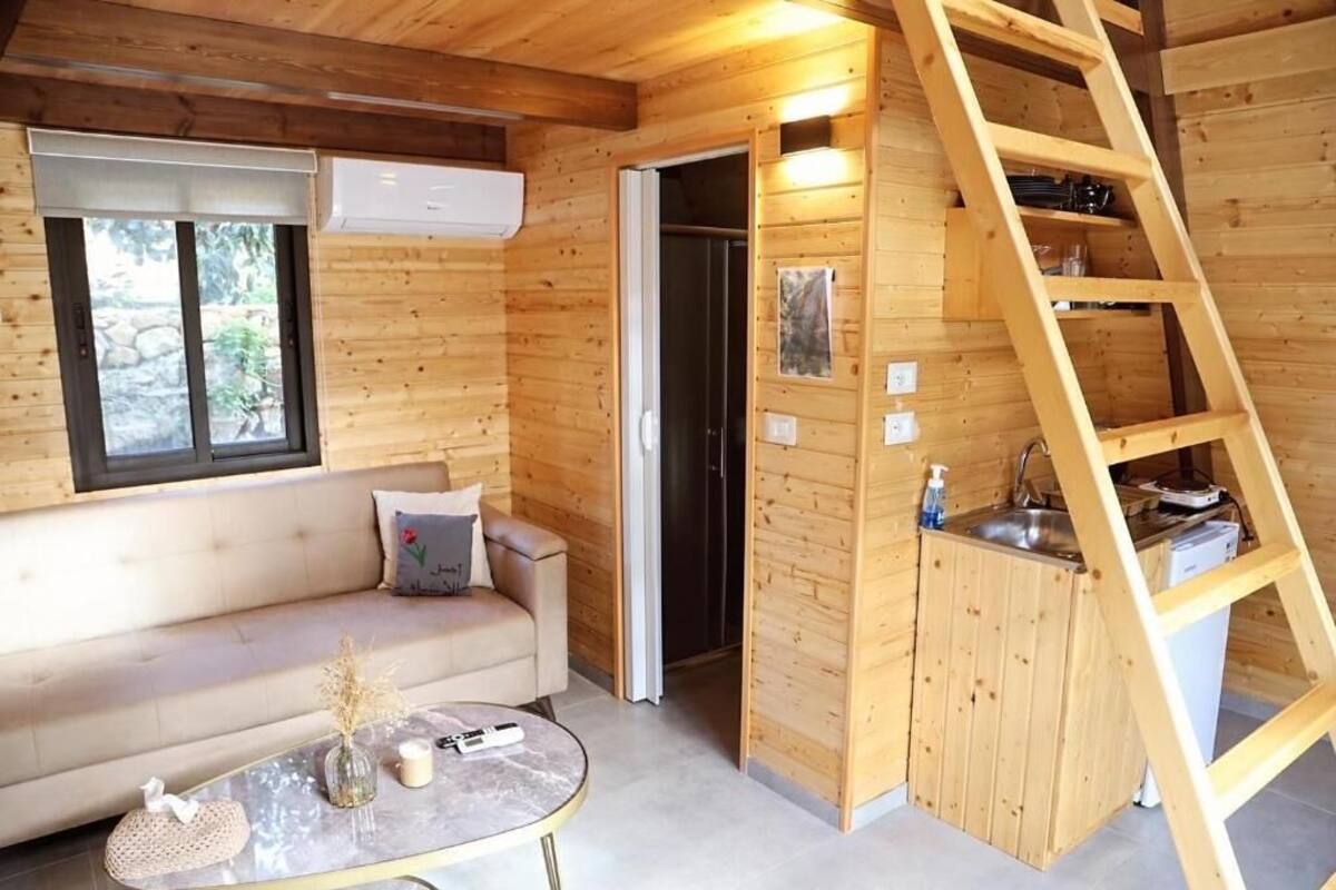 A wooden interior with a sofa, a small table, a ladder, and a kitchen area.