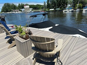 A wooden deck with a boat, chairs, and a potted plant. - Lazy Salmon River Cottage - 2 Bedrooms (Pulaski)