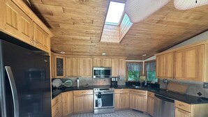 Una cocina con armarios de madera, un refrigerador de acero inoxidable y un tragaluz.