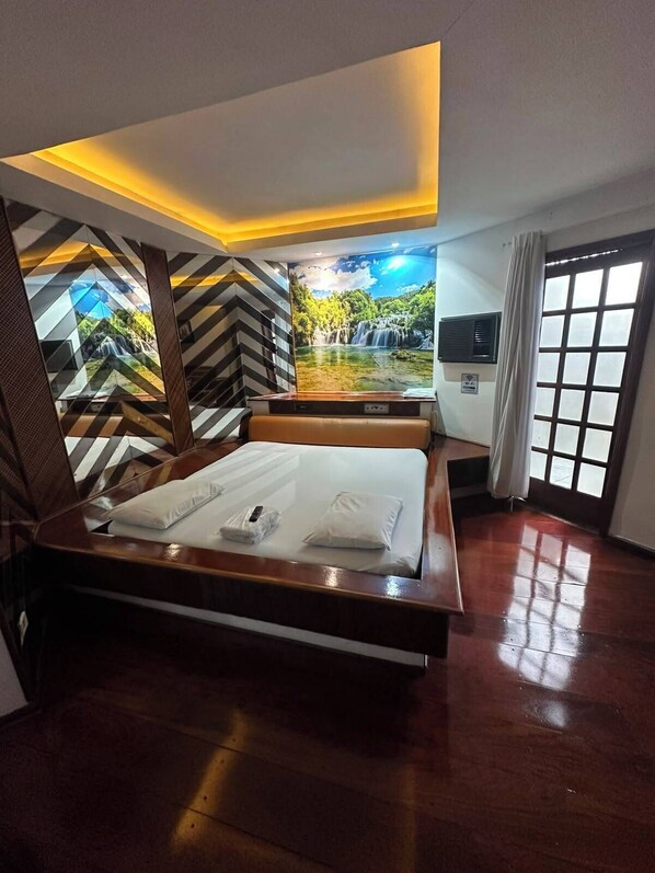 A hotel room with a bed, a large window, and a view of a waterfall.