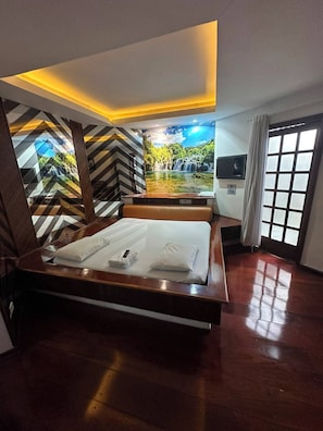 Habitación de hotel con una cama, un ventanal y vistas a una cascada.