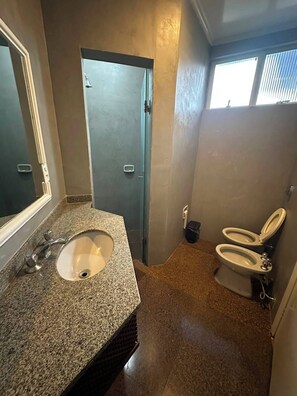 A compact bathroom with a granite countertop sink, a mirror, and a toilet. - Johnnys Motel-Hotel (Cornélio Procópio)