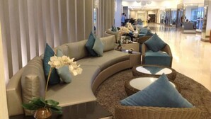 En moderne hotellobby med en buet sofa, fletstole og et glastæppe.