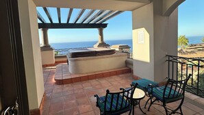 Un balcon extérieur avec vue sur la mer, une pergola et un espace détente avec deux chaises.