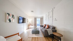 A modern living room with a sofa, ottoman, and a small table.