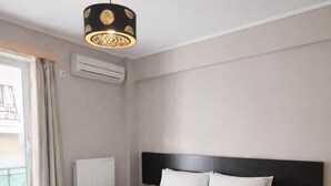 Une chambre d’hôtel avec un grand lit, une table de chevet noire, un globe terrestre et une fenêtre avec des rideaux.