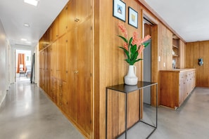 A hallway with wooden cabinets, a white vase with flowers, and a metal table. - Serene Home Near Rose Bowl with Hot Tub (Pasadena)