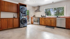 Una cocina con armarios de madera, horno integrado, lavavajillas y un ventanal grande.