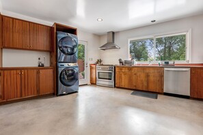 A kitchen with wooden cabinets, a built-in oven, a dishwasher, and a large window. - Serene Home Near Rose Bowl with Hot Tub (Pasadena)