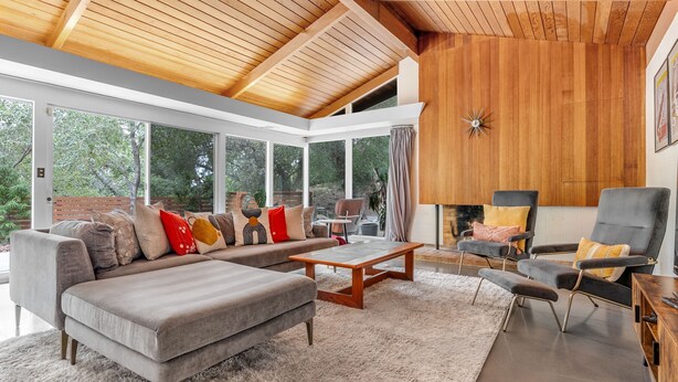 Una sala moderna con sofá, sillones, una mesa de centro y chimenea.