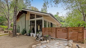 Una casa moderna con un amplio ventanal de vidrio, un camino de piedra y una valla de madera.