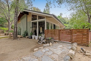 A modern house with a large glass window, a stone pathway, and a wooden fence. - Serene Home Near Rose Bowl with Hot Tub (Pasadena)