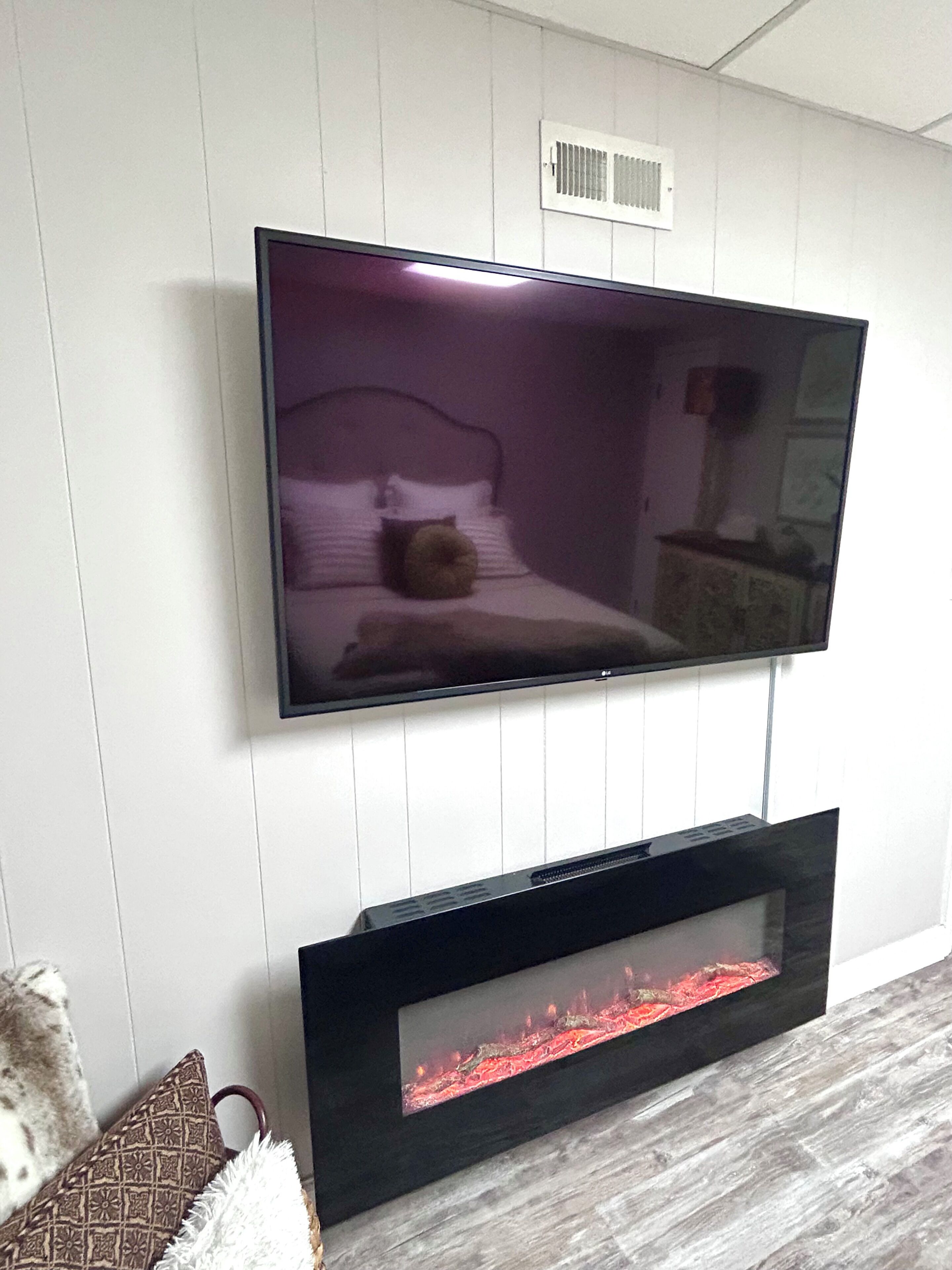 A flat-screen TV mounted on a wall above a fireplace.