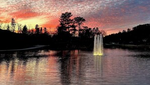 A tranquil lake with a fountain, surrounded by trees and a sunset sky. - Lakeview 1BR/1BA guest suite, pickleball, fishing, close to Asheville & BRP. (Weaverville)