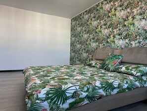 Un dormitorio con una cama, una pared con estampado floral y una pared lisa.