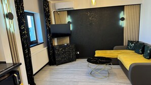A modern bedroom with a bed, a TV, a small table, and a sofa.